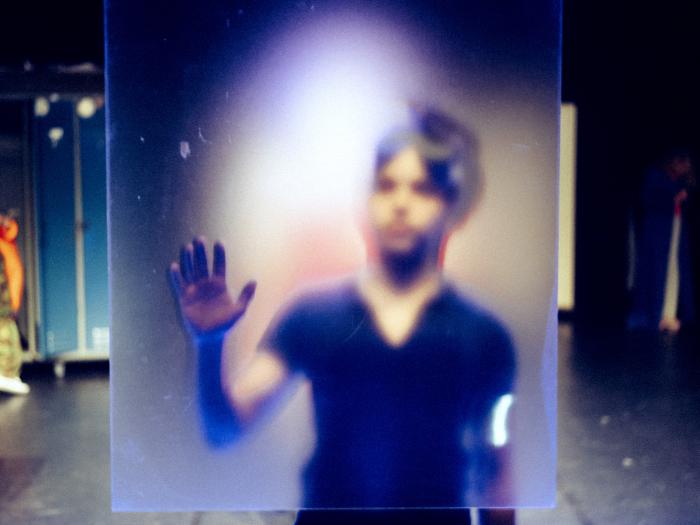 Barn bag plexiglas-plade med den ene hånd på den. Sløret billede