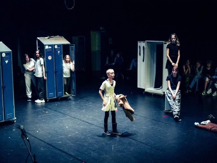 Børn på en mørk scene med skabe rundt omkring. En står midt på scenen og råber. De øvrige står omkring og kigger på